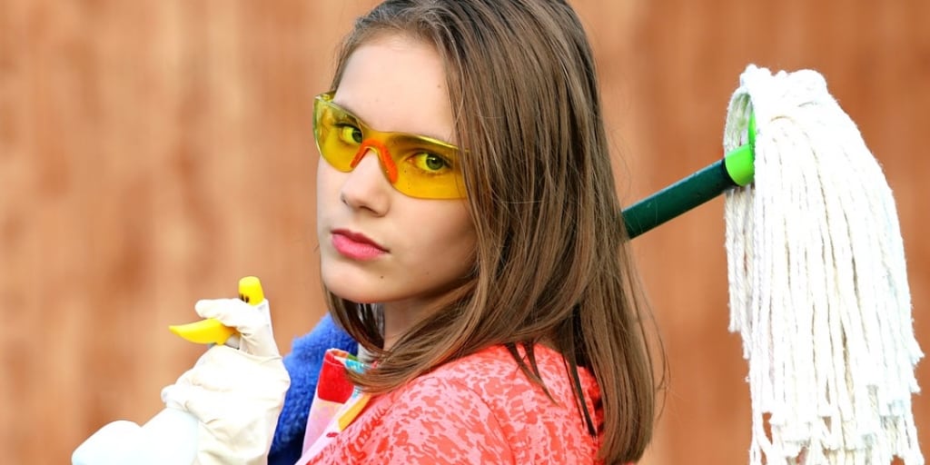 woman with proctetive glasses, gleaning gloves and a mop